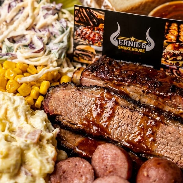 Ernie's Smokehouse platter with ribs, brisket, sausage, coleslaw, corn, and potato salad.